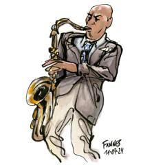 Joshua Redman: Joshua Redman in a grey suit playing tenor saxophone, colour