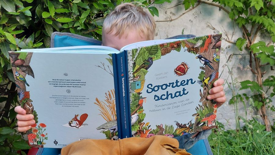Photo: a child reading Soortenschat in the garden