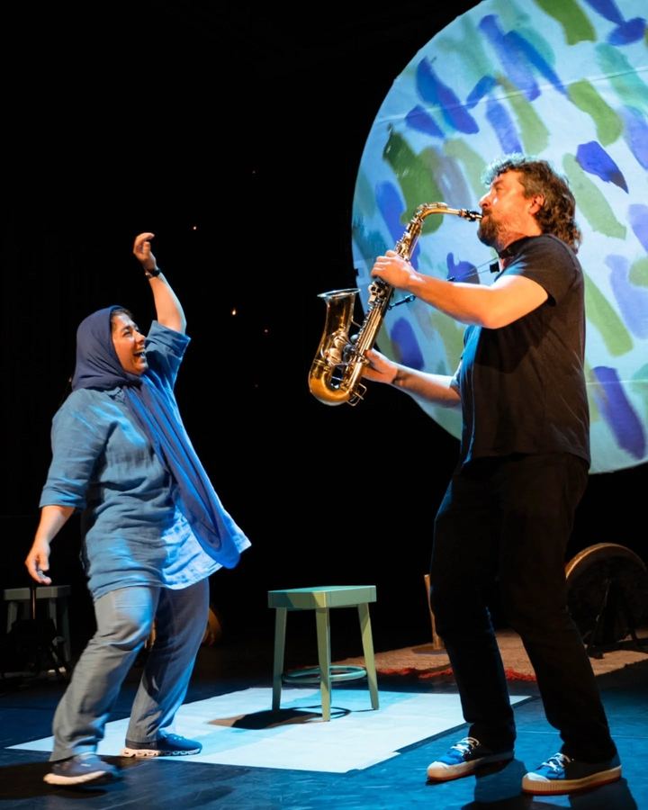 Stage photo: Farnoosh Khodadadeh dancing beside saxophonist Joachim Thys