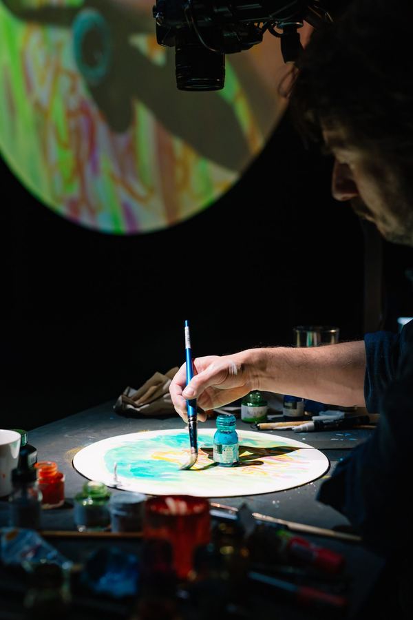 Stage photo: Pieter Fannes painting on a round surface under the camera