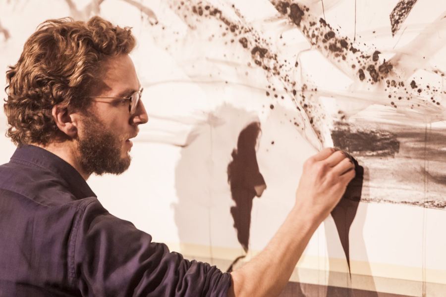 Stage photo: close-up of an artist smudging charcoal with his hand